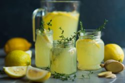 Lemonade drink. Lemonade in the jug and glass jars with lemons, ginger and thyme
